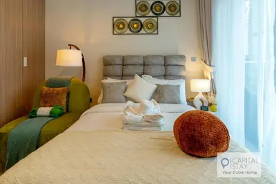 a bedroom with a large bed and a chair at Cozy Apartments in Azizi Riviera Dubai in Dubai