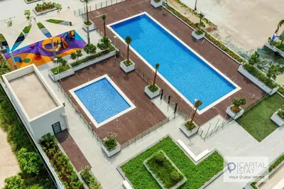 an overhead view of two swimming pools in a resort at Cozy Apartments in Azizi Riviera Dubai in Dubai