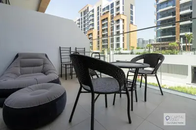 a patio with chairs and a table and a couch at Cozy Apartments in Azizi Riviera Dubai in Dubai