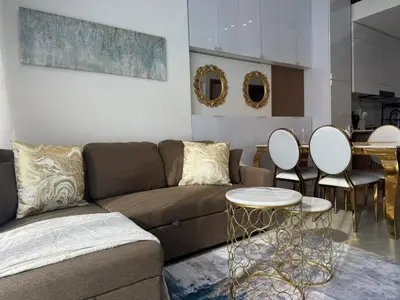 a living room with a couch and a table and chairs at Stylish 1BR Skyline Views JVC Dubai in Dubai