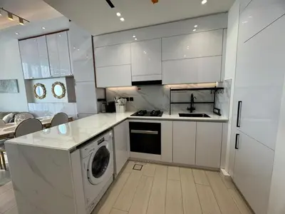 a kitchen with white cabinets and a washing machine at Stylish 1BR Skyline Views JVC Dubai in Dubai