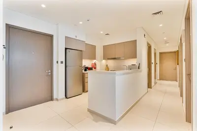 a white kitchen with a counter and a refrigerator at Amazing 3BR APT Near Burj Khalifa and Dubai Mall in Dubai