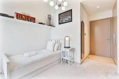 a white bedroom with a white couch and a table at Amazing 3BR APT Near Burj Khalifa and Dubai Mall in Dubai