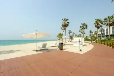 a beach with chairs and an umbrella and the ocean at High-end Beachfront 4BR Duplex with Patio Sea and Burj View in Dubai