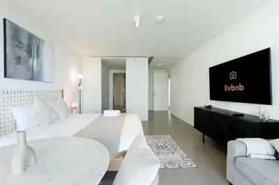 a white bedroom with a bed and a tv on a wall at High-end Beachfront 4BR Duplex with Patio Sea and Burj View in Dubai