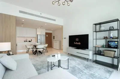 a living room with a couch and a tv and a kitchen at Sea View 2B Beachfront Luxury Emaar Beachfront in Dubai