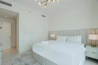 a bedroom with a large white bed and a chandelier at Sea View 2B Beachfront Luxury Emaar Beachfront in Dubai