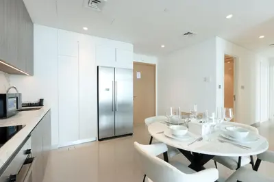 a white kitchen with a table and chairs and a refrigerator at Sea and Palm View 2B Beachfront Luxury Emaar Beachfront in Dubai