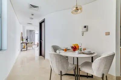 a white dining room with a white table and chairs at DAYF-SKGMAR Upgraded Huge High-Floor Studio with Dubai Frame View in Dubai