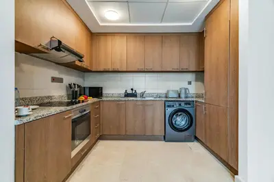 a kitchen with wooden cabinets and a washing machine at DAYF-SKGMAR Upgraded Huge High-Floor Studio with Dubai Frame View in Dubai