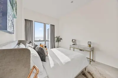 a white bedroom with a bed and a window at Luxury 2BR at Signature Grande - Next to Dubai Mall & Burj Khalifa in Dubai