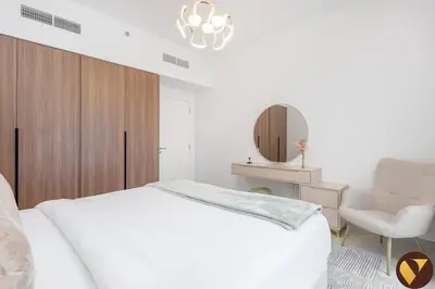 a bedroom with a bed and a chair and a mirror at Vogue Madinat Jumeirah Living Jadeel near Burj AlArab, Two-Bedroom Apartment with Large Balcony and Pool View, Access to All Amenities in Dubai