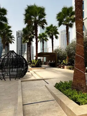 a park with palm trees in a city with buildings at Stunning Bay View Studio in Center of Dubai in Dubai