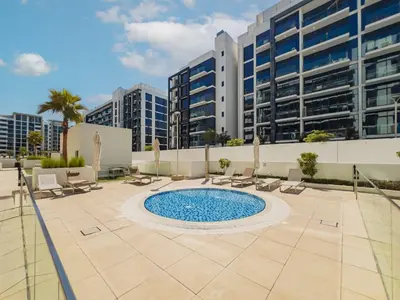 a swimming pool with chairs and a building at Elite Escape - 1 BHK Getaway in Azizi Riviera 18 in Dubai