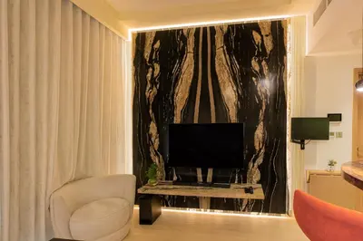 a living room with a television and a chair at Elite Escape - 1 BHK Getaway in Azizi Riviera 18 in Dubai