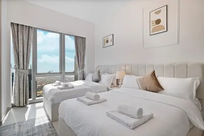 two white beds in a room with a large window at Luxury 2BR Sea Burj views Khalifa infinity pool in Dubai