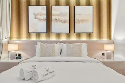a bedroom with a white bed with three pictures on the wall at FIRST CLASS 1BR Luxury Meets Simplicity in Dubai