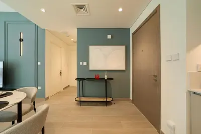 a hallway with blue walls and a table and chairs at Chic & Sunny 1BR Escape At Grove Creek Beach Access in Dubai