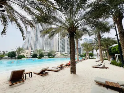 a swimming pool with lounge chairs and palm trees at Chic & Sunny 1BR Escape At Grove Creek Beach Access in Dubai
