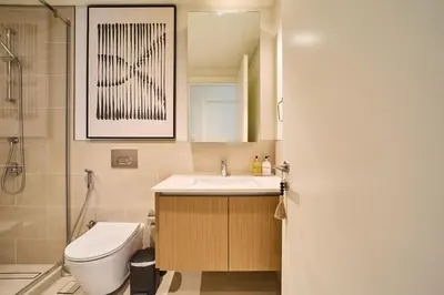 a bathroom with a sink and a toilet and a mirror at Chic & Sunny 1BR Escape At Grove Creek Beach Access in Dubai