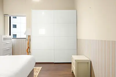 a white bedroom with a bed and a dresser at FIRST CLASS 3BR Sea View Near JBR Beach in Dubai