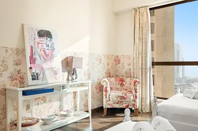 a bedroom with a bed and a chair and a window at FIRST CLASS 3BR Sea View Near JBR Beach in Dubai