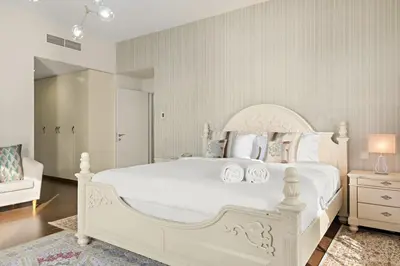 a white bedroom with a large white bed and a couch at FIRST CLASS 3BR Sea View Near JBR Beach in Dubai