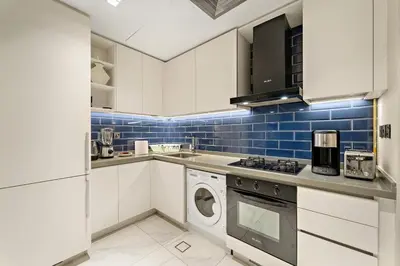 a kitchen with white cabinets and a washer and dryer at FIRST CLASS 2BR Pool View and near Dubai Mall in Dubai