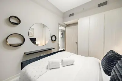a bedroom with a white bed and a mirror at FIRST CLASS 1BR Modern Serenity in Dubai