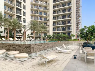 a resort with a swimming pool and chairs and a building at FIRST CLASS 1BR Modern Serenity in Dubai
