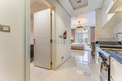 a kitchen with a large white refrigerator in a room at Furnished Studio Near Circle Mall, Close to Parks, Jogging Tracks, Bus Stops And Grocery Stores - Damac Ghalia, JVC by Deluxe Holiday Homes in Dubai