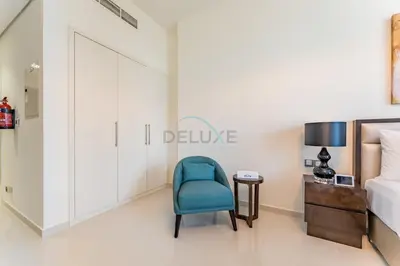 a bedroom with a blue chair and a bed at Furnished Studio Near Circle Mall, Close to Parks, Jogging Tracks, Bus Stops And Grocery Stores - Damac Ghalia, JVC by Deluxe Holiday Homes in Dubai
