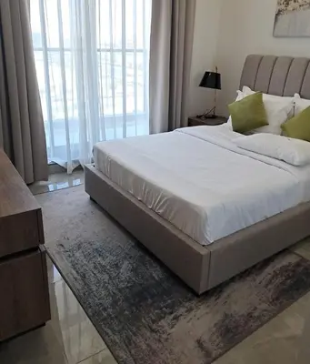 a bedroom with a large bed with white sheets and green pillows at Majestic Retreat - 1BR Dubai in Dubai