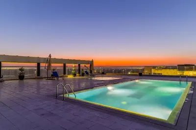 a swimming pool on top of a building with a sunset at Majestic Retreat - 1BR Dubai in Dubai