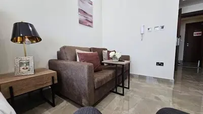 a living room with a couch and a table at Studio Luxe Dubai South in Dubai