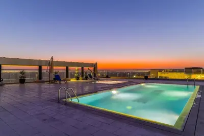 a swimming pool on top of a building with a sunset at Studio Luxe Dubai South in Dubai