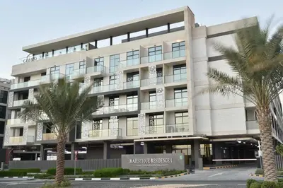 a large building with palm trees in front of it at Studio Luxe Dubai South in Dubai