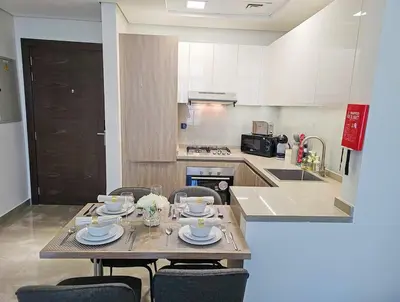 a kitchen with a table and chairs with plates and glasses at The Executive Nest -1BR in Dubai in Dubai