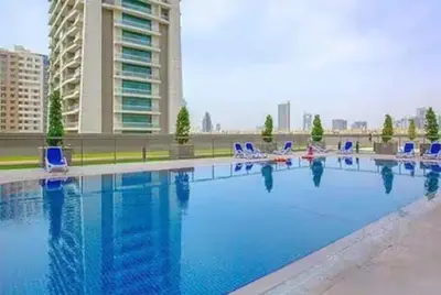 a large swimming pool with blue chairs and a building at Vogue Sports City Elite near First Avenue Mall, One Bedroom Apartment with Balcony and Vibrant Community View, Access to all Amenities in Dubai