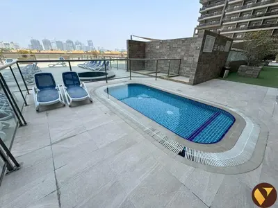 a patio with two chairs and a swimming pool at Vogue Sports City Elite near First Avenue Mall, One Bedroom Apartment with Balcony and Vibrant Community View, Access to all Amenities in Dubai