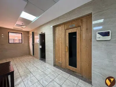 a hallway with a wooden door in a building at Vogue Sports City Elite near First Avenue Mall, One Bedroom Apartment with Balcony and Vibrant Community View, Access to all Amenities in Dubai