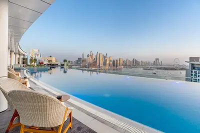 a swimming pool with chairs and a view of the city at Luxury Palm Studio - Skyline Views - Rooftop Pool & Beach Access in Dubai