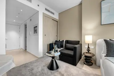 a living room with a black chair and a couch at Luxury Palm Studio - Skyline Views - Rooftop Pool & Beach Access in Dubai