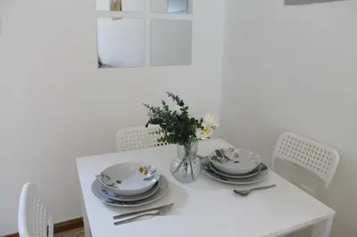 a white table with plates and a vase of flowers at Studio apartment walking distance to metro and beach in Marina in Dubai
