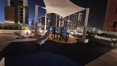 a playground in a city at night with buildings at Azizi Riviera Luxury Studio with Grand Balcony in Dubai