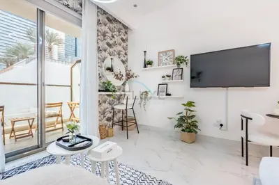 a living room with a flat screen tv on a wall at Just Steps Away from Circle Mall, Right Beside a Park, Near Restaurants, Conveniently Close to a Bus Stop, Lumina Vista Residences, Jumeirah Village Circle by Deluxe Holiday Homes in Dubai