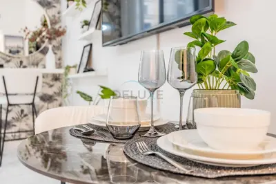 a table with glasses and plates and a bowl at Just Steps Away from Circle Mall, Right Beside a Park, Near Restaurants, Conveniently Close to a Bus Stop, Lumina Vista Residences, Jumeirah Village Circle by Deluxe Holiday Homes in Dubai