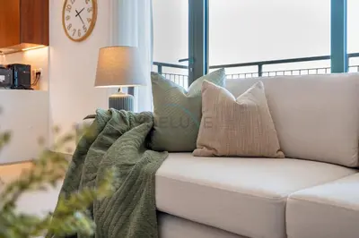 a white couch with pillows on it in a living room at Urban Beachside 2BR with a Glimpse of Burj Khalifa, Near Jumeirah Beaches, Short Drive to Mercato Mall, La Sirene Building 4, Jumeirah by Deluxe Holiday Homes in Dubai