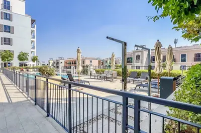 a balcony with a fence and tables and chairs at Urban Beachside 2BR with a Glimpse of Burj Khalifa, Near Jumeirah Beaches, Short Drive to Mercato Mall, La Sirene Building 4, Jumeirah by Deluxe Holiday Homes in Dubai