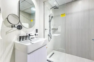 a white bathroom with a sink and a shower at Superhost- 1BR Near Miracle Garden, Pool and Gym, Balcony Arjan in Dubai